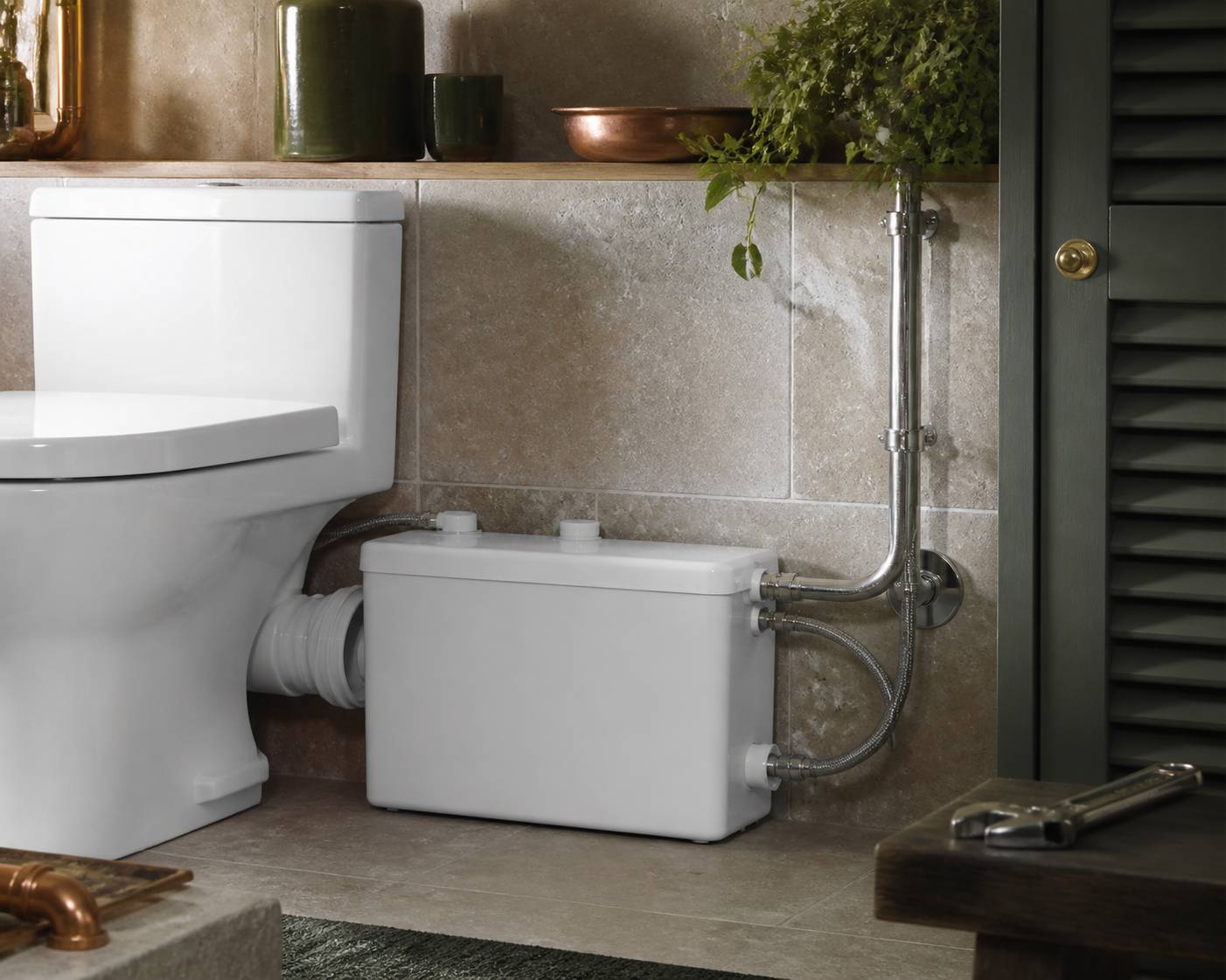 Boîtier de broyeur sanitaire compact avec raccords en inox près d'un WC