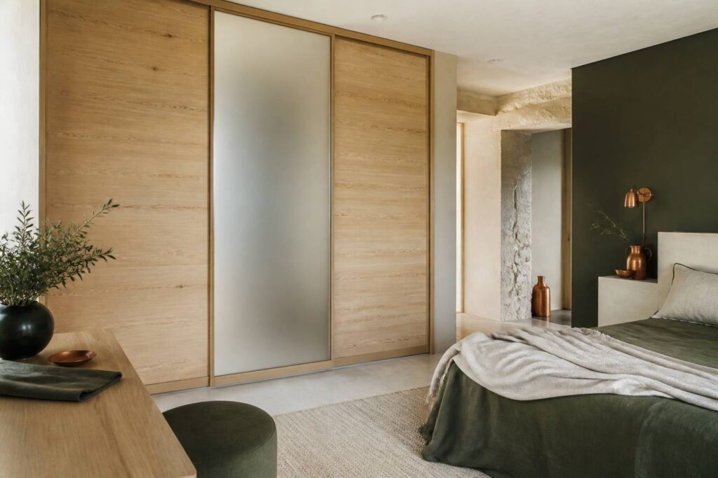 Dressing fermé en bois clair avec portes coulissantes dans une chambre
